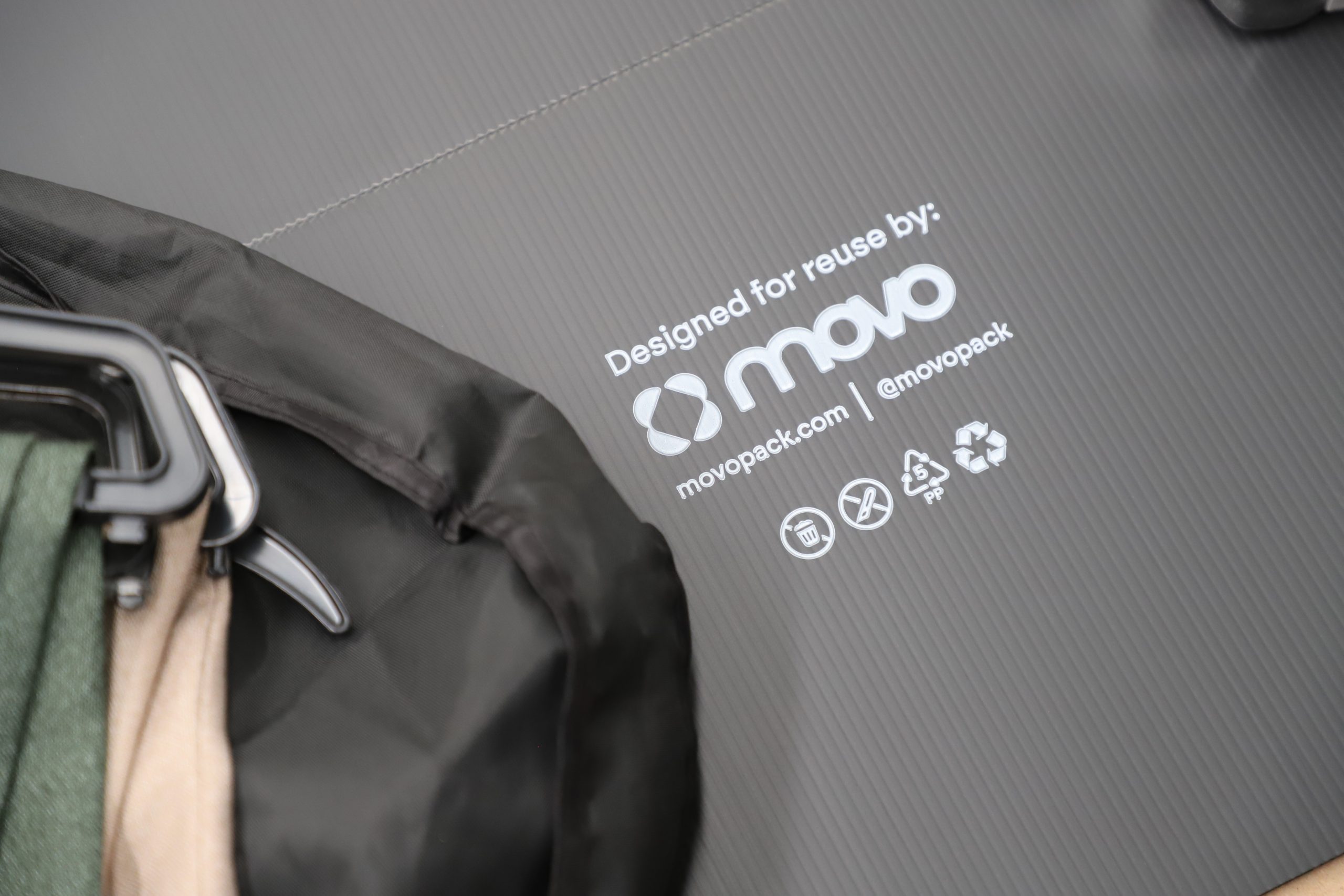 Clothing lying on a black flat pack box with MovoPack logo