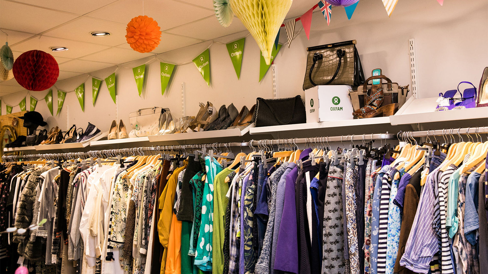 Oxfam store with clothing ril, green bunting and shoes and accessories
